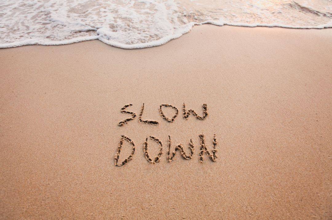 Strand mit Schild 'Slow Down' – Entschleunigen und zur Ruhe kommen