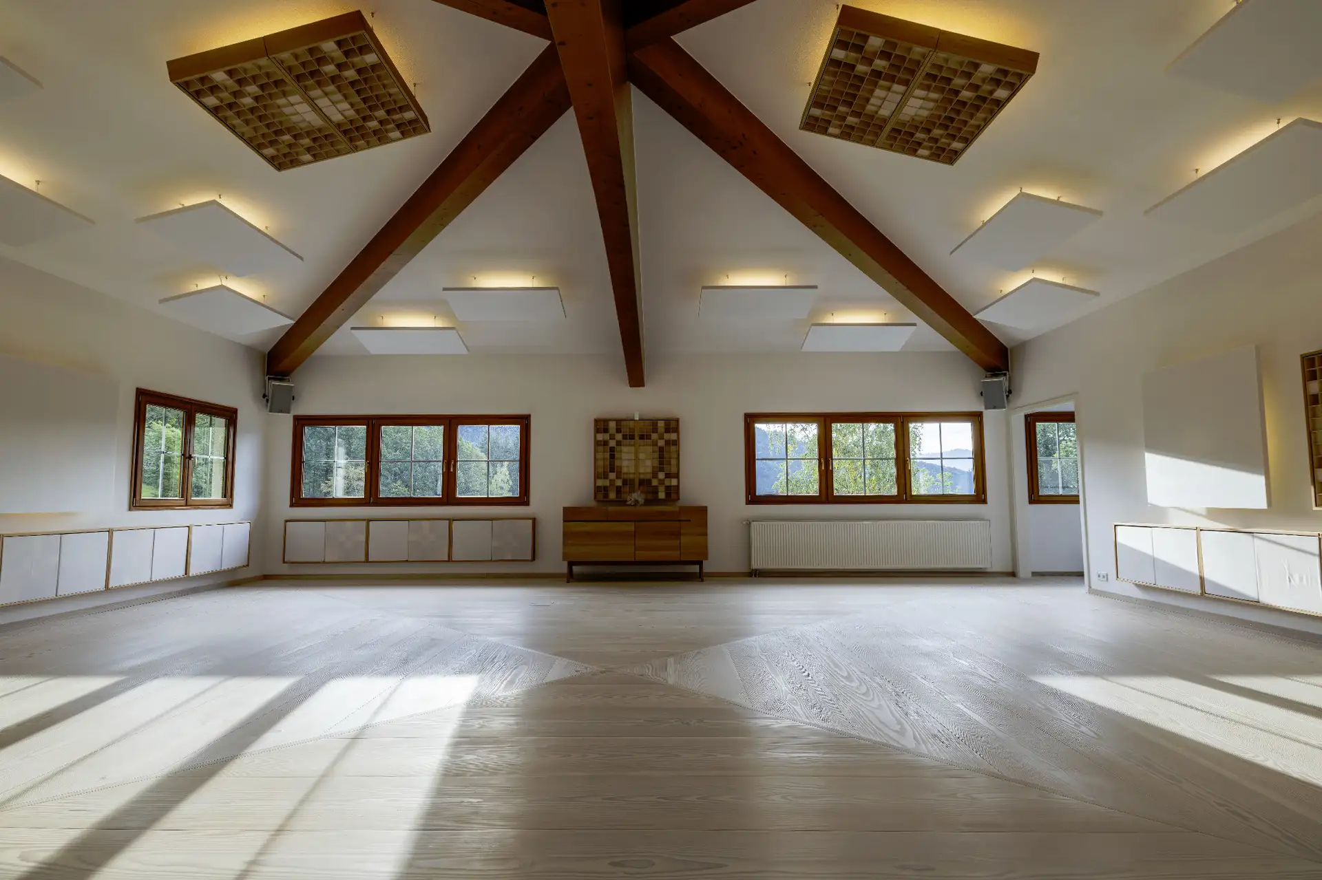 Heller Yoga- und Seminarraum im Retreathaus im Schwarzwald mit Holzdecke, großen Fenstern und ruhiger Atmosphäre für Achtsamkeit und Meditation.