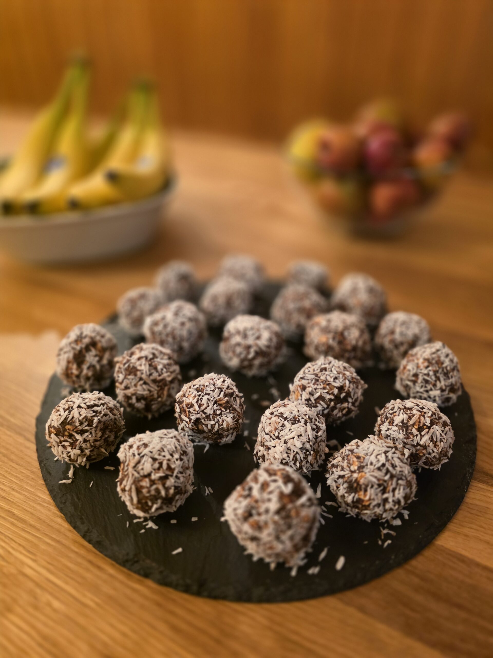 Energy Balls mit Kokosraspeln auf einer Schieferplatte als gesunder Snack